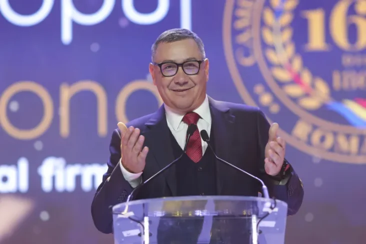 "Fostul premier Victor Ponta vorbind la un eveniment public, exprimându-se cu gesturi animate în timpul unui discurs, în timp ce poartă un costum elegant.