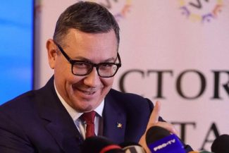 Victor Ponta vorbind la un microfon în timp ce anunță candidatura independentă pentru președinția României, înconjurat de mass-media."