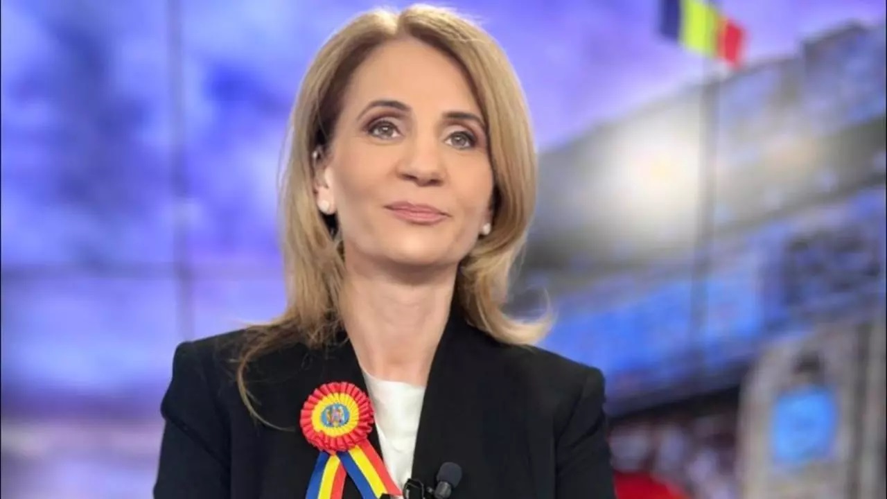 Anca Alexandrescu, prezentatoarea emisiunii Culisele Statului Paralel, zâmbind în timp ce poartă o cocardă tricoloră, reprezentând demnitatea și patriotismul în mass-media românească.