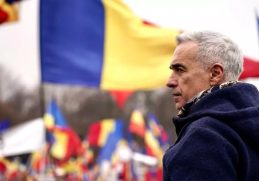 Călin Georgescu în fața mulțimii de suporteri, cu steagurile României în fundal, în timpul campaniei sale electorale