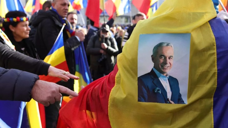 Protestatari ținând un steag al României cu imaginea lui Călin Georgescu în timpul manifestației pentru drepturi și democrație.