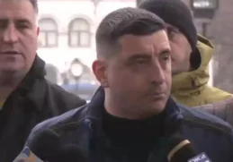 George Simion înconjurat de manifestanți, adresându-se presei într-un mediu urban, cu o expresie serioasă și determinată