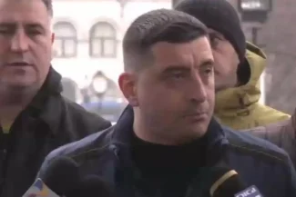 George Simion înconjurat de manifestanți, adresându-se presei într-un mediu urban, cu o expresie serioasă și determinată