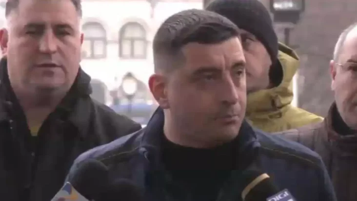 George Simion înconjurat de manifestanți, adresându-se presei într-un mediu urban, cu o expresie serioasă și determinată