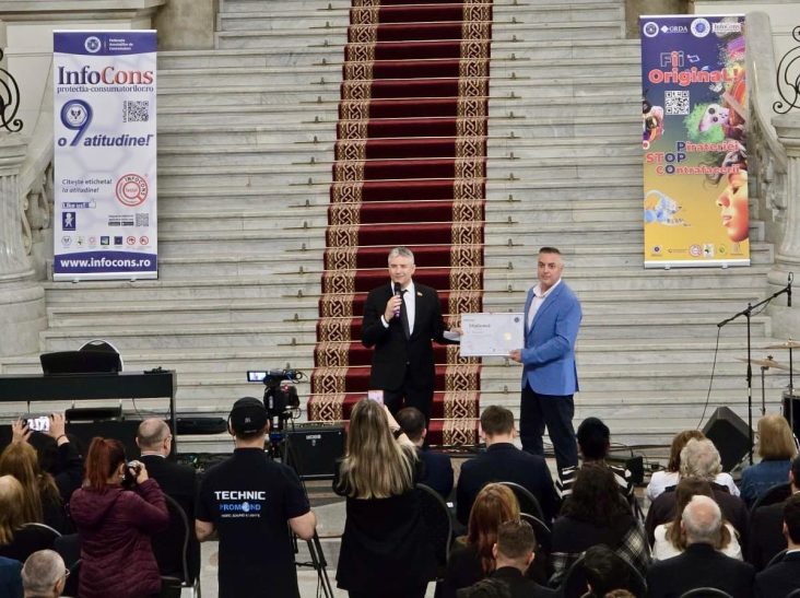 Reprezentantul ICI București primește diploma de recunoaștere din partea InfoCons pe scena principală a unui eveniment oficial dedicat Zilei Mondiale a Proprietății Intelectuale, desfășurat la Palatul Parlamentului, în fața unei audiențe formate din oficiali, presă și participanți.