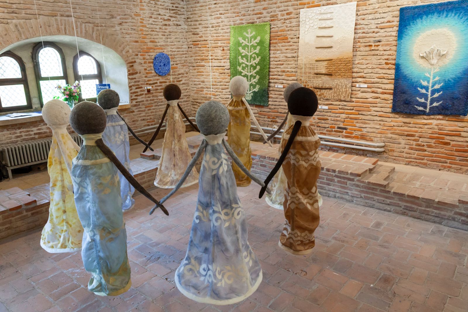 Instalația tridimensională „Hora, armonie universală” expusă la Palatul Mogoșoaia, cu opt siluete umane din lână împâslită dispuse într-un cerc simbolic, înconjurate de lucrări textile parietale semnate de artista Nicoleta Bică Bucșaru.