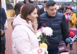 Anca Alexandrescu, alături de George Simion, discută cu jurnaliștii și locuitorii Capitalei în timpul unei acțiuni de campanie, ținând în mână flori oferite de susținători.