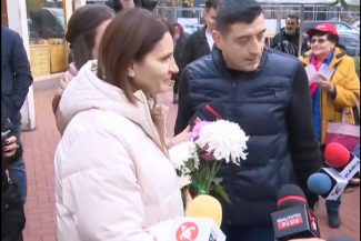 Anca Alexandrescu, alături de George Simion, discută cu jurnaliștii și locuitorii Capitalei în timpul unei acțiuni de campanie, ținând în mână flori oferite de susținători.
