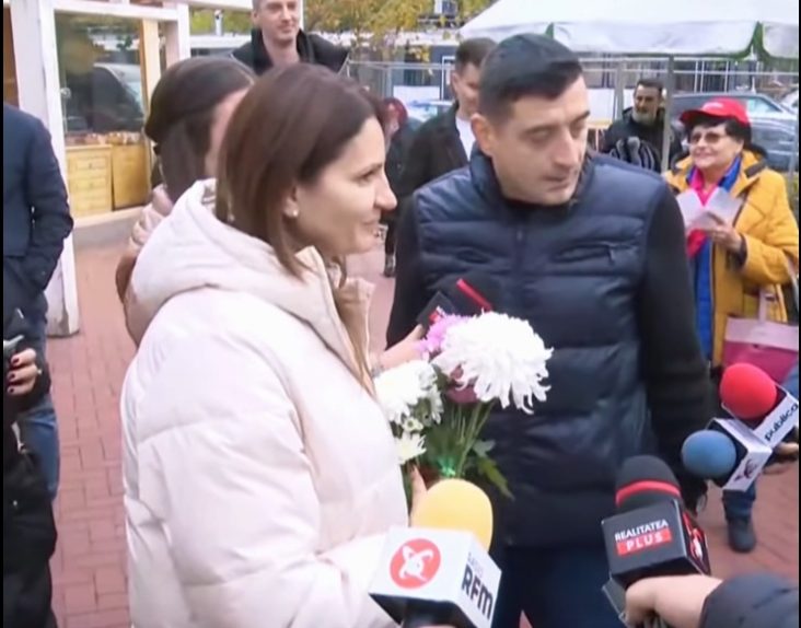 Anca Alexandrescu, alături de George Simion, discută cu jurnaliștii și locuitorii Capitalei în timpul unei acțiuni de campanie, ținând în mână flori oferite de susținători.