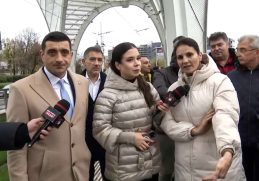 Anca Alexandrescu și George Simion la stația de tramvai Eroii Revoluției, criticând investiția de 5,3 milioane de euro într-o structură decorativă, în timp ce bucureștenii așteaptă tramvaiul în frig și ploaie.