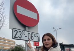 Anca Alexandrescu arătând un semn rutier care interzice parcarea noaptea lângă un hipermarket din București, propunând ca aceste spații să fie deschise pentru locuitori.
