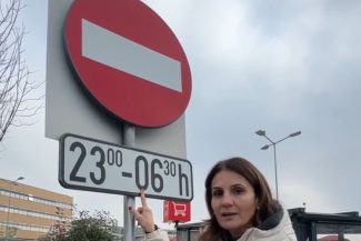 Anca Alexandrescu arătând un semn rutier care interzice parcarea noaptea lângă un hipermarket din București, propunând ca aceste spații să fie deschise pentru locuitori.
