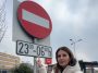 Anca Alexandrescu arătând un semn rutier care interzice parcarea noaptea lângă un hipermarket din București, propunând ca aceste spații să fie deschise pentru locuitori.