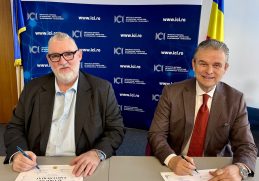 Adrian-Victor Vevera, Director General ICI București, și Ioan Lucian, Președinte UNPR, semnează acordul de cooperare pentru dezvoltarea programelor de formare profesională, la sediul ICI București, în fața unui panou oficial.