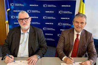 Adrian-Victor Vevera, Director General ICI București, și Ioan Lucian, Președinte UNPR, semnează acordul de cooperare pentru dezvoltarea programelor de formare profesională, la sediul ICI București, în fața unui panou oficial.