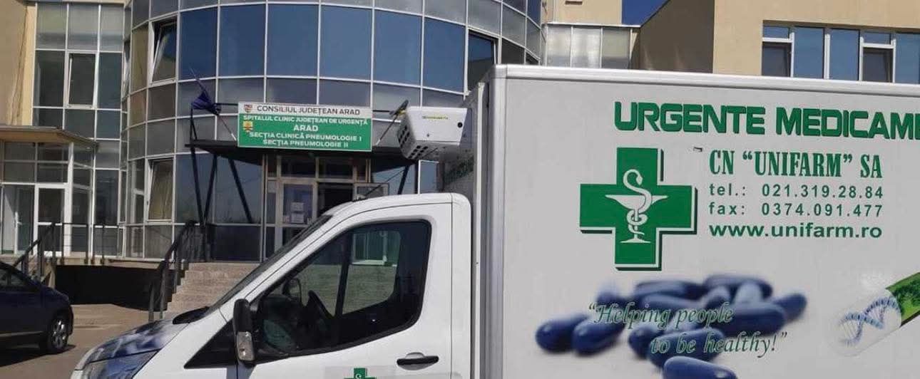 Autoutilitară CN Unifarm SA utilizată pentru livrări de medicamente de urgență, parcată în fața unei unități spitalicești din România.