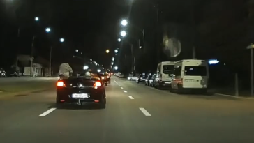 Maşină decapotabilă, aparent lăsată să ruleze din inerţie, pe un bulevard din Drobeta Turnu Severin. Persoana aflată pe locul şoferului lasă volanul şi se ridică în picioare